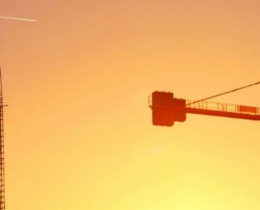 Construction site showing tower cranes and other construction machinery at sunrise.