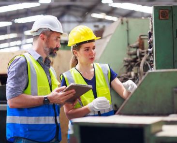 Mann und Frau in Schutzkleidung an einer Maschine