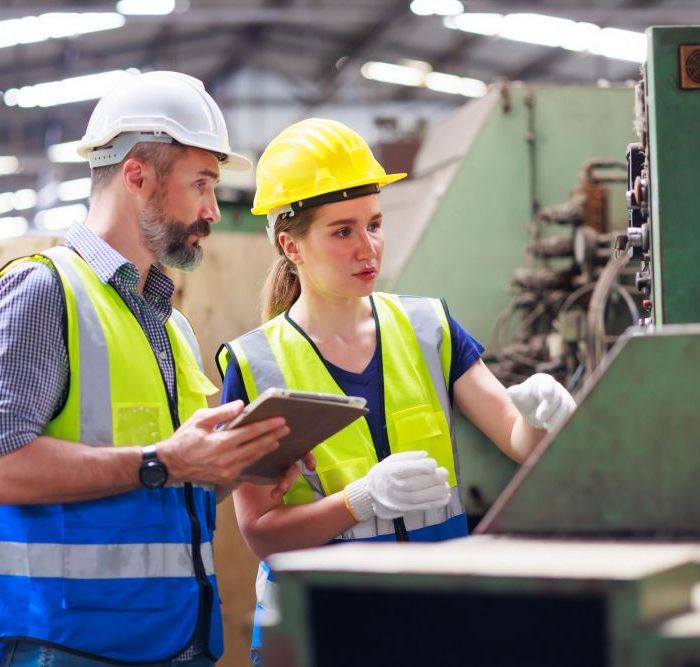 Mann und Frau in Schutzkleidung an einer Maschine